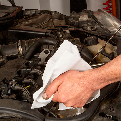 Manos de hombre con un trapo limpiando una pieza de motor