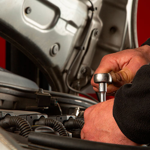 Primer plano de manos sobre motor usando una llave