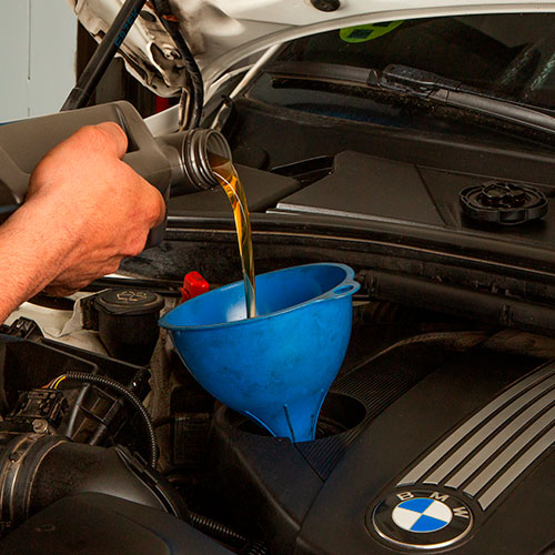 Motos con un embudo puesto y una lata de aceite vertiendo sobre él