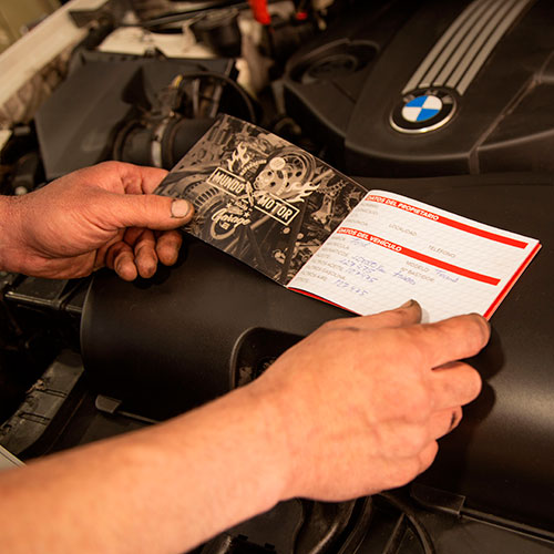 Manos de hombre sujetando una cartilla de revisiones mecánicas