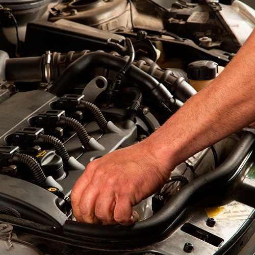 Mano de hombre desenroscando una pieza en un motor de coche