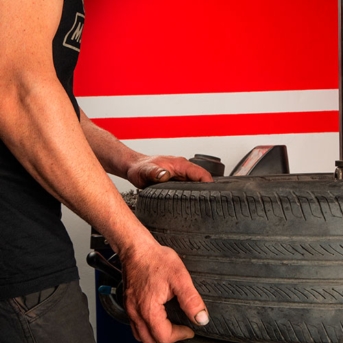 Hombre sujetando un neumático en una máquina