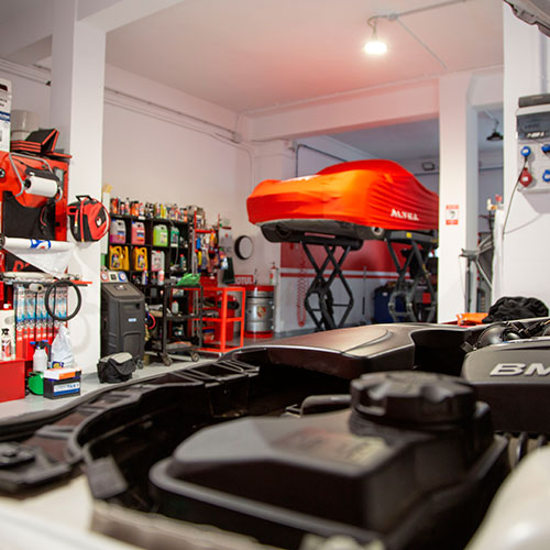 Vista del interior de un taller con un coche subido en un elevador
