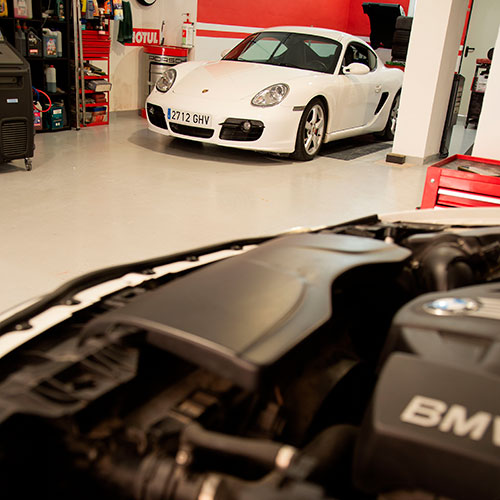 Vista del interior de un taller con un coche blanco de la marca Porsche dentro