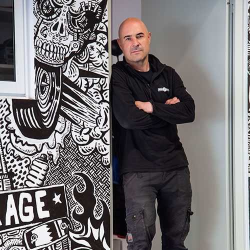 Hombre con ropa de trabajo apoyado en el marco de una puerta